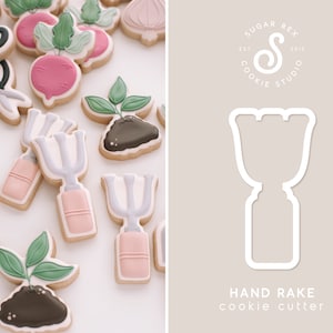 May include: A white cookie cutter in the shape of a hand rake. The cookie cutter is on a light brown background with the text "HAND RAKE cookie cutter" below it. The text "SUGAR REX COOKIE STUDIO EST 2018" is in a circle above the cookie cutter.