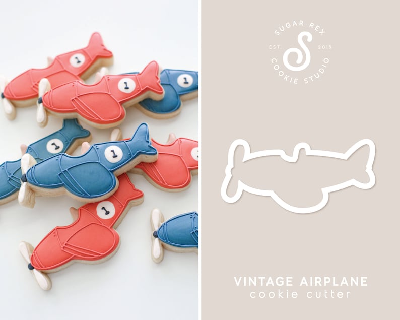 May include: A cookie cutter in the shape of a vintage airplane. The cutter is white and outlined in a thin white line. The cutter is on a light brown background with the text "Vintage Airplane cookie cutter" below it.