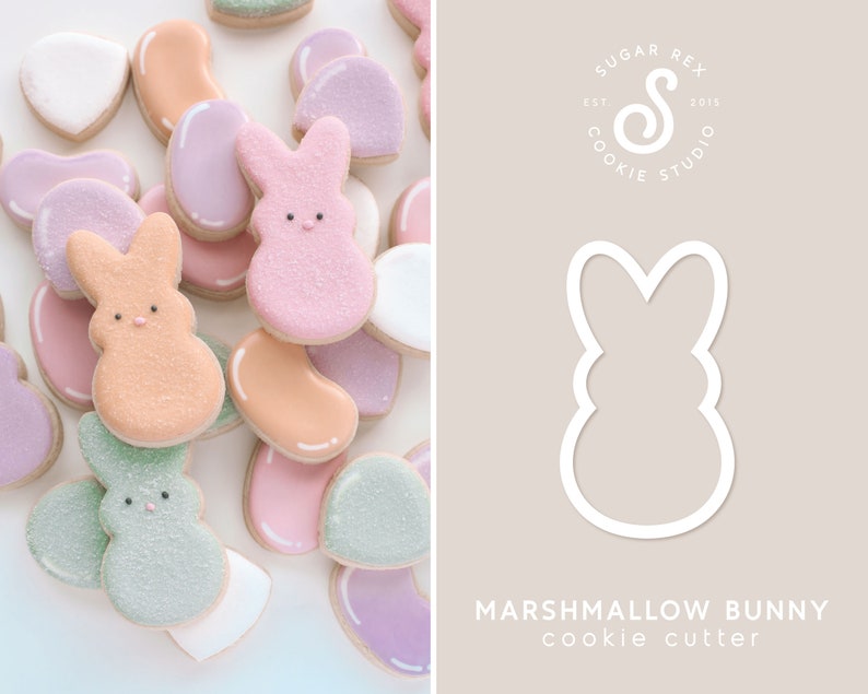 May include: A cookie cutter in the shape of a marshmallow bunny. The cutter is white and is shown on a light brown background. The text "MARSHMALLOW BUNNY cookie cutter" is below the cutter.