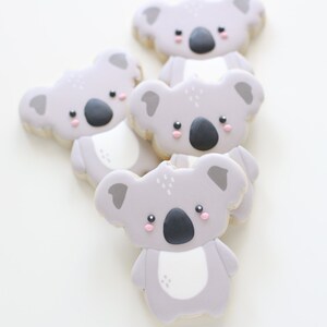 May include: Four gray koala cookies with pink cheeks and black noses. The cookies are stacked on top of each other.
