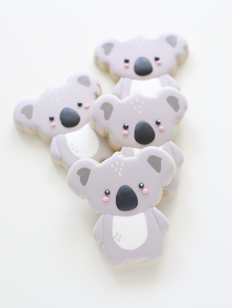 May include: Four gray koala cookies with pink cheeks and black noses. The cookies are stacked on top of each other.