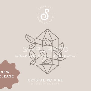 May include: A line drawing of a crystal cookie cutter with a vine design. The cutter is in the shape of a geometric crystal with leaves and stems. The text "SAMPLE PHOTO coming soon" is written below the cutter. The text "NEW RELEASE" is in a starburst shape below the text. The text "CRYSTAL W/ VINE cookie cutter" is below the starburst.