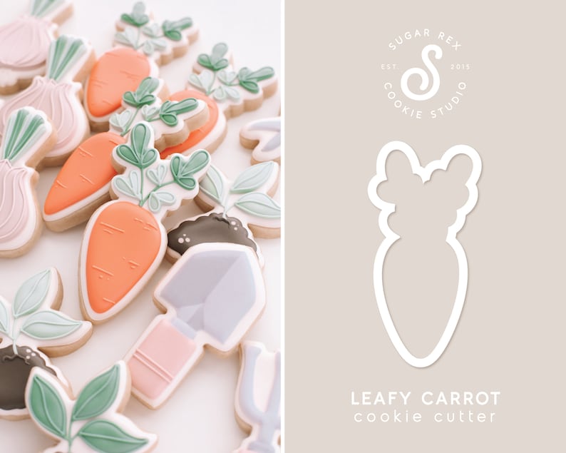 Puede incluir: Un cortador de galletas blanco en forma de zanahoria con hojas. El cortador est&aacute; sobre un fondo marr&oacute;n claro con el texto "Leafy Carrot cookie cutter" y un logotipo para Sugar Rex Cookie Studio.