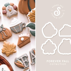 May include: A set of cookie cutters for making fall-themed cookies. The cutters are in the shape of a pumpkin, a pie slice, a coffee cup, a leaf, and a turkey. The cutters are made of white plastic and are shown on a light gray background. The text "FOREVER FALL collection" is printed below the cutters.