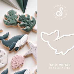 Op de afbeelding: Een blauwe walvis koekjesvormer, een populair ontwerp voor het bakken en decoreren van koekjes. De vormer is gemaakt van metaal en heeft een gladde, afgeronde vorm. De afbeelding toont ook verschillende gedecoreerde koekjes, waaronder een blauwe walvis, schelpen en zeesterren.