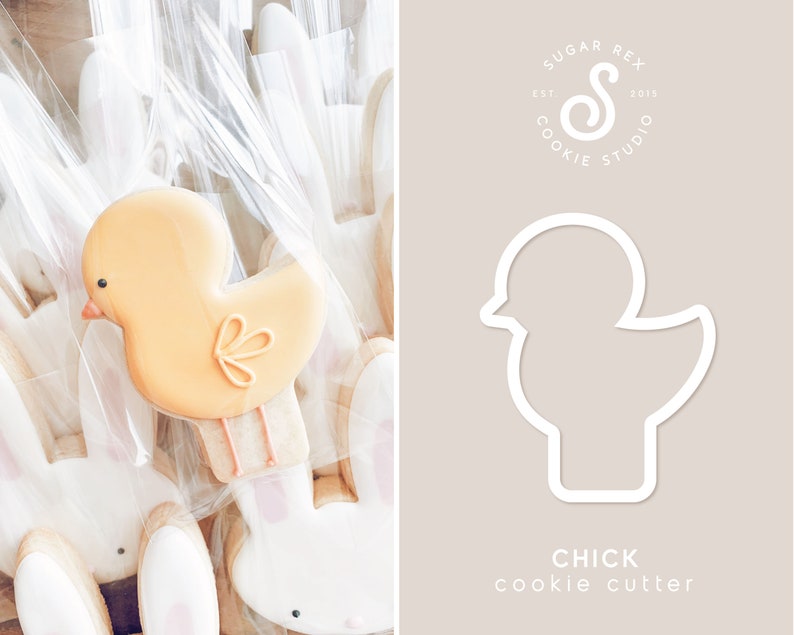 Op de afbeelding: Een paasafbeelding met een gele kuikenvormige koek met oranje details, verpakt in doorzichtig cellofaan. De contour van de koekjessteker is ook afgebeeld, met de tekst "CHICK cookie cutter" en het logo Sugar Rex Cookie Studio.