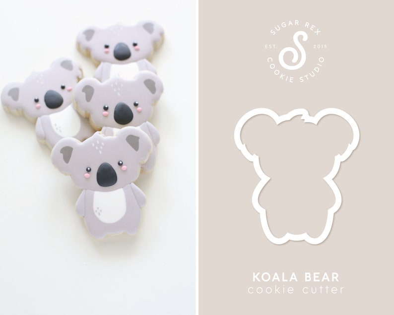 May include: A set of four gray koala bear cookies with pink cheeks and black noses. The cookies are stacked on top of each other. A white koala bear cookie cutter is shown on the right side of the image. The text "KOALA BEAR cookie cutter" is below the cookie cutter.