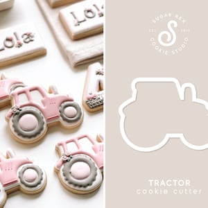 May include: Pink and gray tractor cookie cutter. The cutter is shown with a pink and gray tractor cookie. The cookie cutter is for making cookies.