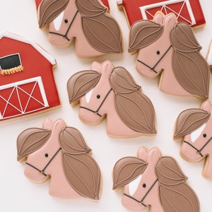 Pu&ograve; includere: Un set di biscotti di zucchero decorati con fienili rossi e cavalli marroni. I biscotti sono decorati con glassa bianca e dettagli neri.