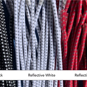 May include: Close-up of three bundles of reflective cords in black, white, and ruby-red. Each cord has a dotted pattern. Text at the bottom reads "Reflective Black", "Reflective White", and "Reflective Ruby-Red".