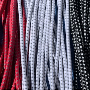 May include: Close-up of several strands of elastic cord in red, white, and black. The cords have a dotted pattern and are tightly packed together. The cords are likely used for crafting or other DIY projects.