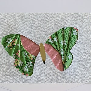 May include: A green and pink butterfly origami card with a white background. The butterfly is made of patterned paper and has a gold body.