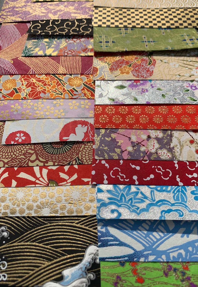 May include: A collection of colorful patterned Japanese washi paper strips. The paper features a variety of designs, including floral, geometric, and abstract patterns. The paper is perfect for scrapbooking, card making, and other craft projects.