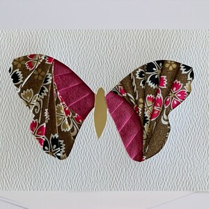 May include: A handmade greeting card featuring a paper butterfly with brown, pink, and gold accents. The butterfly is cut out of the card and has a floral pattern.
