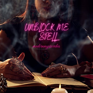 Op de afbeelding: Een vrouw in een zwarte jurk met een ketting en ringen, zittend aan een tafel met een boek dat open ligt voor haar. De tekst "UNBLOCK ME SPELL" is geschreven in roze neonletters boven het boek. De tekst "modernmysticvibes" is geschreven onder het boek.