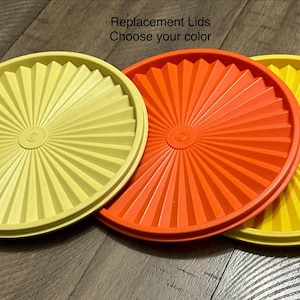 May include: Three replacement lids in yellow, orange, and yellow. The lids feature a radial design with a central circular detail. The text "Replacement Lids Choose your color" is visible in the image.