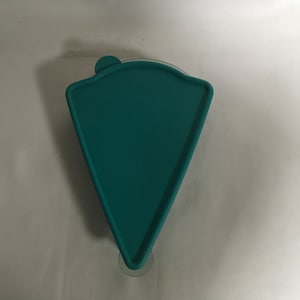Op de afbeelding: Een tealblauw plastic deksel voor een taartvorm. Het deksel heeft een afgeronde rand en een zuignap aan de onderkant.