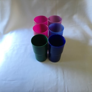 Peut inclure: Six gobelets en plastique de différentes couleurs, dont rose, bleu, vert et violet. Les gobelets sont empilés les uns sur les autres.