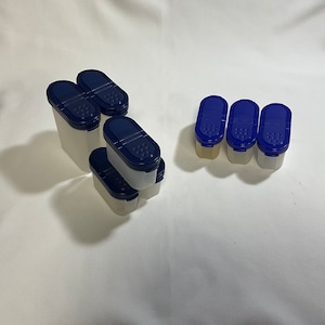 May include: Set of nine white plastic spice containers with blue lids. The lids have small holes for sprinkling spices.