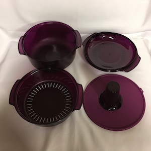May include: A set of four purple plastic containers with lids. The containers are different sizes and have a variety of uses, including steaming food.