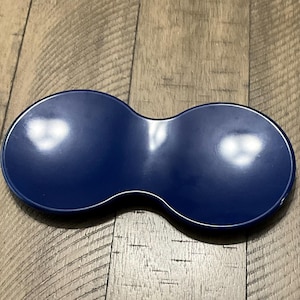 May include: A blue silicone spoon rest shaped like a figure eight. The rest has a smooth, glossy finish.