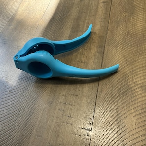May include: A blue plastic citrus juicer with a lever to squeeze the fruit. The juicer is designed to extract juice from lemons, limes, and oranges.