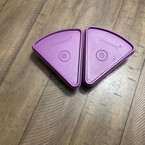 May include: Two purple plastic pie plate lids with the word "Tupperware" printed on them.