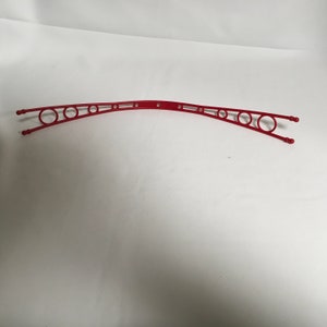 Peut inclure: Séchoir à linge en plastique rouge avec plusieurs ouvertures circulaires.