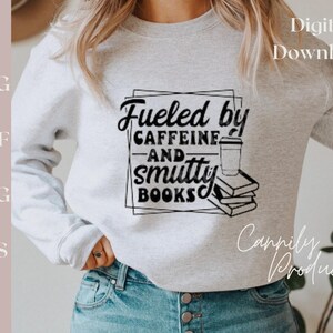 Puede incluir: Una sudadera gris con el texto "Fueled by Caffeine and Smutty Books" en negro. Una taza de caf&eacute; y una pila de libros est&aacute;n incluidos en el dise&ntilde;o. El texto "Digital Download" est&aacute; en la esquina superior derecha de la imagen.