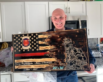 May include: A rectangular wooden wall plaque featuring a charred American flag design with a thin red line. It includes a Naval District Washington Fire EMS emblem, a firefighter silhouette, and text reading Training Chief-Firefighter-Station 13 NDWFD 2001-2021 20" x 36".