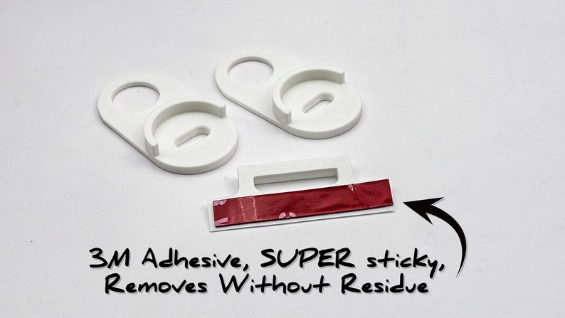 May include: Two white plastic wall mounts with a red 3M adhesive strip. The adhesive is labeled "SUPER sticky, Removes Without Residue".
