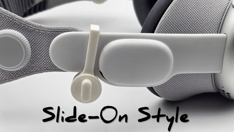 May include: Close-up of a white headset strap with a slide-on style adjustment mechanism. The strap is made of a soft, gray fabric and has a white plastic slider.