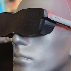 Op de afbeelding: Een persoon draagt een paar zwarte en grijze RayNeo slimme brillen. De bril heeft een strak, modern ontwerp en wordt gedragen op een mannequinhoofd.