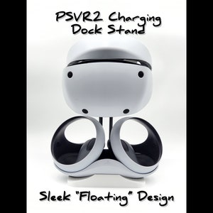 Puede incluir: Un soporte de carga PSVR2 blanco con un diseño "flotante" elegante. El soporte tiene dos brazos curvos que sujetan el auricular VR en su lugar.