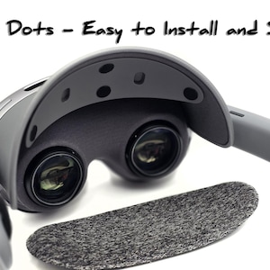 May include: A gray VR headset with the text "Vecro Dots - Easy to Install and Secure." The headset has two lenses and a dark gray foam pad. The design is modern and sleek, with a focus on ease of use.