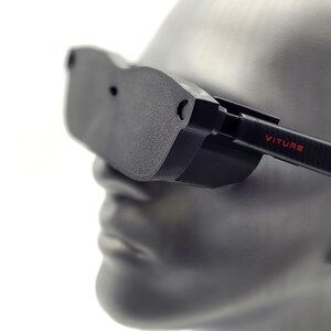 May include: Black VR headset with the word "VITURE" in red on the side. The headset is mounted on a gray mannequin head. The headset has a sleek, modern design, with a focus on functionality and a minimalist aesthetic.