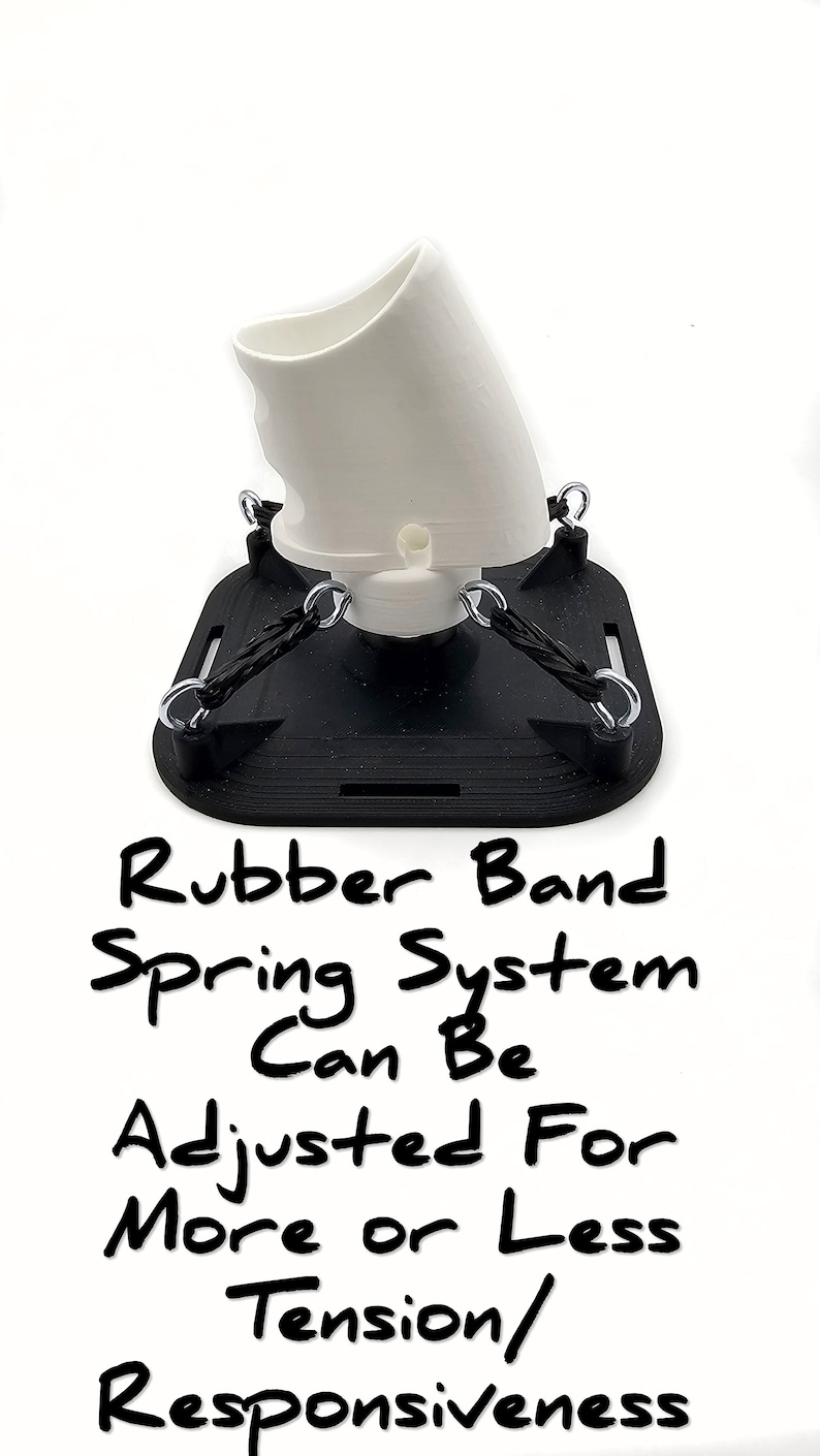 Puede incluir: Objeto blanco impreso en 3D con una base negra y bandas de goma. El texto dice "Rubber Band Spring System Can Be Adjusted For More or Less Tension/Responsiveness".