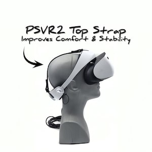 Op de afbeelding: Een witte virtual reality headset met een zwarte bovenband. De band is gelabeld "PSVR2 Top Strap Improves Comfort & Stability".