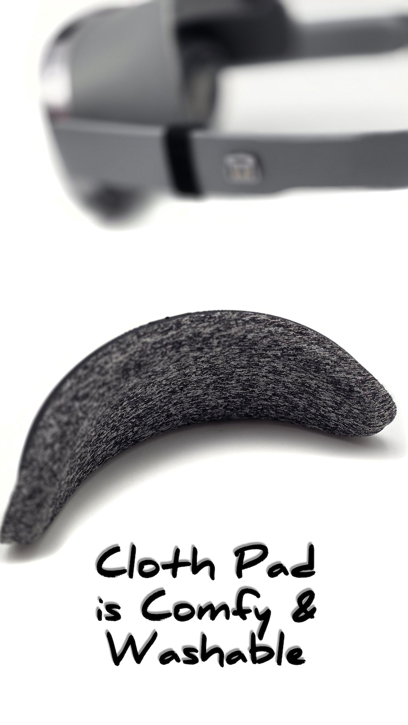May include: A curved, gray cloth pad with a textured surface. The text "Cloth Pad is Comfy & Washable" is written in black. The image also shows a blurred gray object in the background.