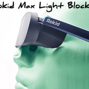 May include: A pair of black light blockers for a virtual reality headset. The light blockers are made of a soft, flexible material and have a blue and white "Rokid" logo on the side.