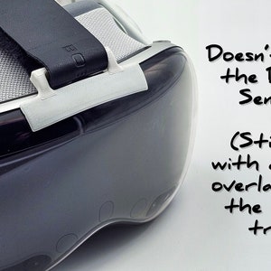 May include: A white plastic VR headset strap accessory with the text "Doesn't Block the Depth Sensors (Stick it with a little overlap over the metal trim)" written in black marker.