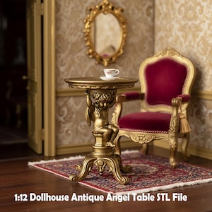 Può includere: Un tavolino dorato in miniatura con una base a forma di angelo, che sorregge un piano rotondo. Una piccola tazza da tè e un piattino sono appoggiati sul tavolo. Il tavolo fa parte di una scena di casa delle bambole, con una sedia di velluto rosso e uno specchio ornato sullo sfondo.