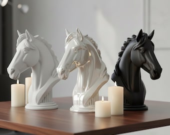 Peut inclure: Trois sculptures de têtes de chevaux, blanches, nacrées et noires, sont posées sur une table marron. Les sculptures sont des bustes avec des crinières et des traits du visage détaillés. Des bougies allumées de différentes tailles sont placées devant les sculptures.