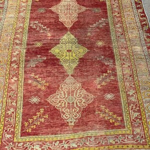 Könnte beinhalten: Ein roter Vintage-Teppich mit einem geometrischen Muster in Gelb und Creme. Der Teppich hat einen Fransenrand und ist aus Wolle.