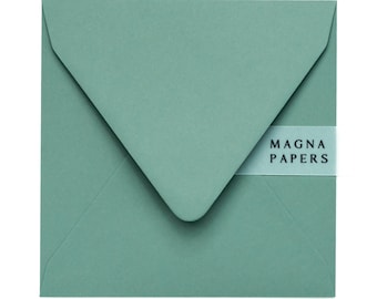 May include: A teal green envelope with a white label that says "MAGNA PAPERS" in black text.