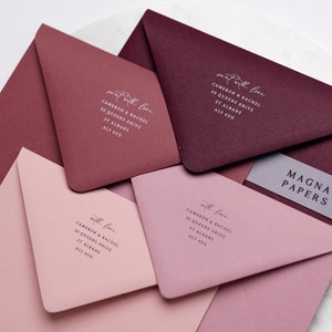May include: Four envelopes in different shades of pink and burgundy with white calligraphy that reads "sent with love" and the address "Cameron & Rachel, 30 Queens Drive, St Albans, ALS 4UG". A clear sticker with the text "MAGNA PAPERS" is on the top envelope.