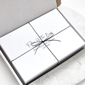 May include: A stack of white cards tied with black string. The cards have the text "Father of the Bride" and an address printed on them.