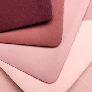 May include: Four pieces of paper in shades of pink and burgundy, layered on top of each other.