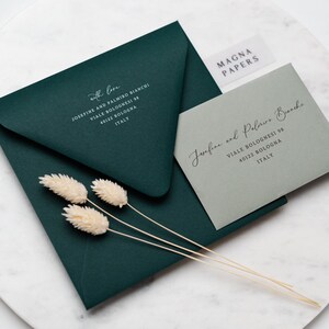May include: Two envelopes, one green and one gray, with white text on them. The green envelope has the text "with love" and an address. The gray envelope has the text "Josefine and Palmiro Bianchi" and an address. The text "MAGNA PAPERS" is on a white sticker on the gray envelope.