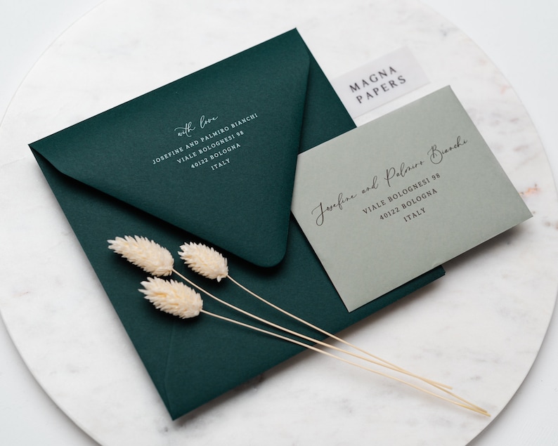 May include: Two envelopes, one green and one gray, with white text on them. The green envelope has the text "with love" and an address. The gray envelope has the text "Josefine and Palmiro Bianchi" and an address. The text "MAGNA PAPERS" is on a white sticker on the gray envelope.
